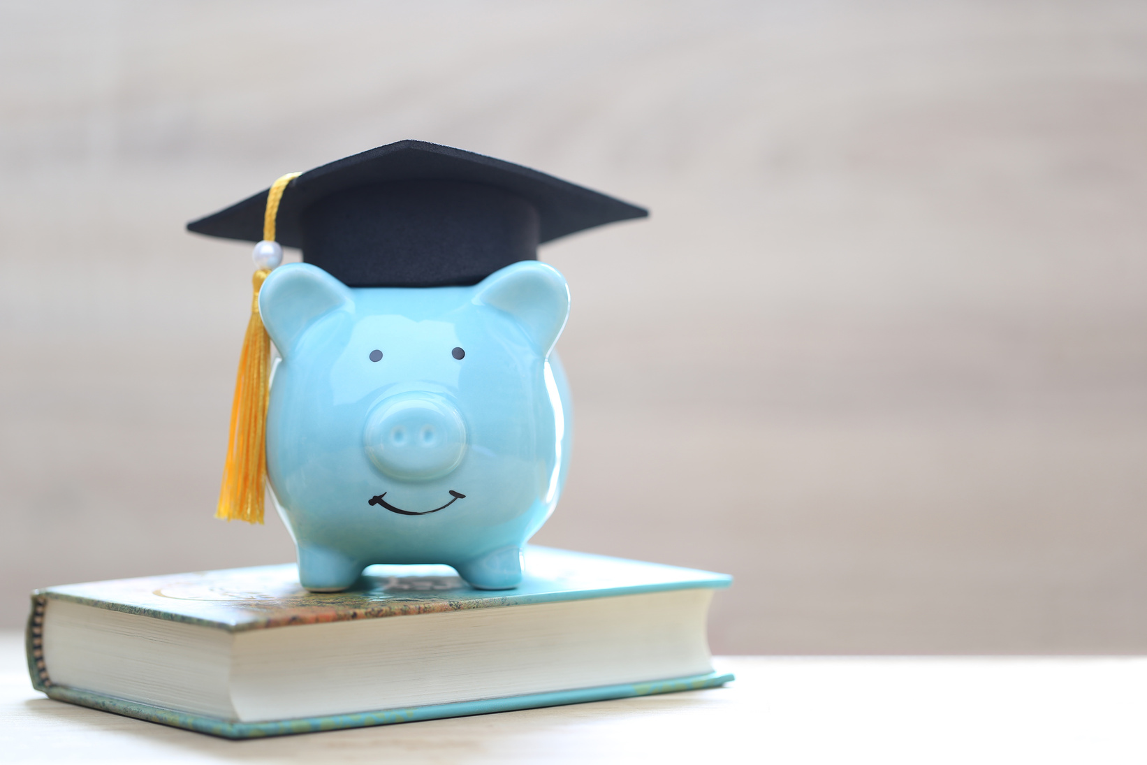 Graduation hat on piggy bank and a books on white   background, Saving money for education concept